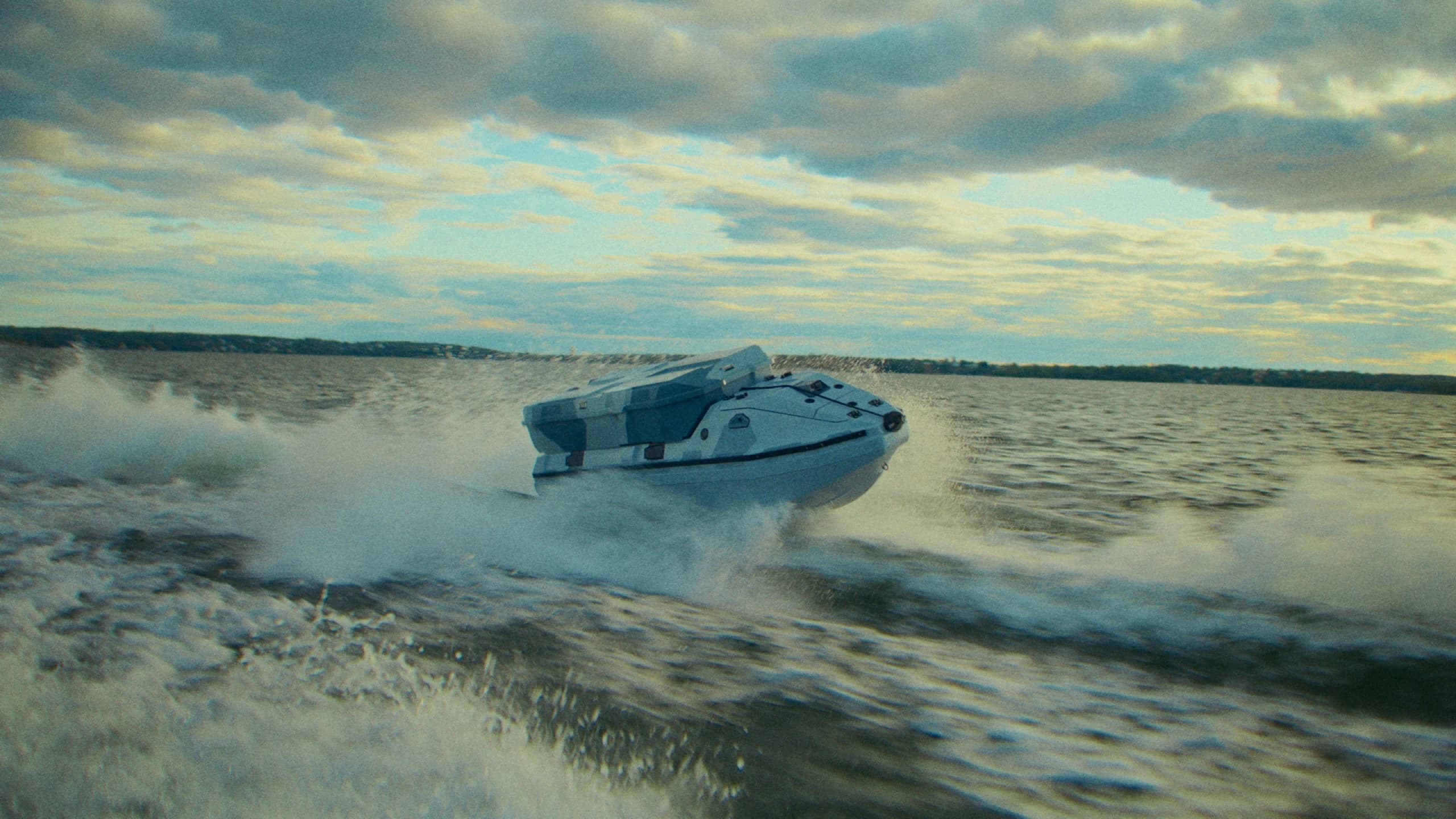 Camouflaged Nautrik vessel planing at speed through spray